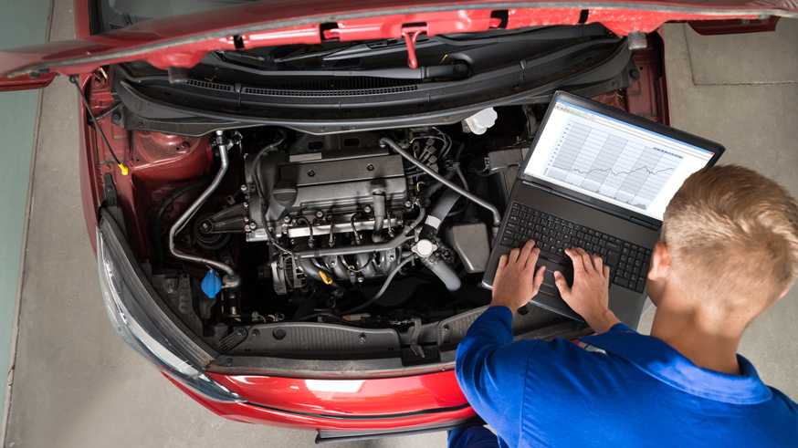 Mechanic Examining Car Engine With Help Of Laptop